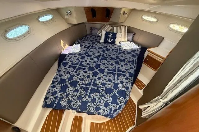 Slide: The Image of 2023 Cutwater C-30 Sedan cabin with nautical-themed bedding and elegant wood flooring. - 21