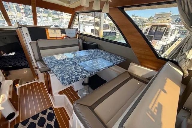 Slide: The Image of 2023 Cutwater C-30 Sedan interior with dining area, featuring a patterned table and cushioned seating. - 12
