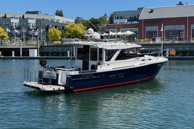Slide: The Image of 2023 Cutwater C-30 Sedan boat docked in a marina with urban backdrop. - 9