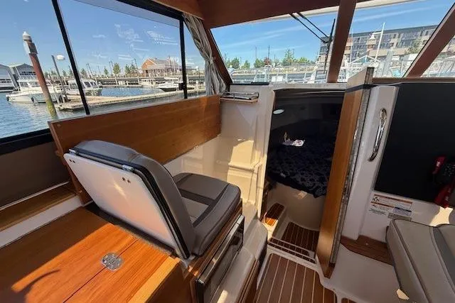 Slide: The Image of 2023 Cutwater C-30 Sedan interior with seating, wood accents, and marina view. - 17