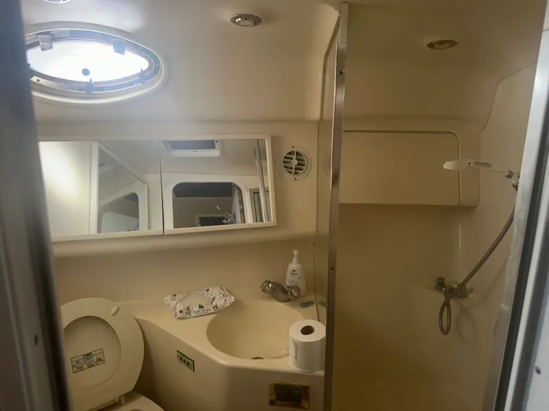 Slide: The Image of Interior view of a boat bathroom with toilet, sink, and shower. A porthole lets in light. - 17