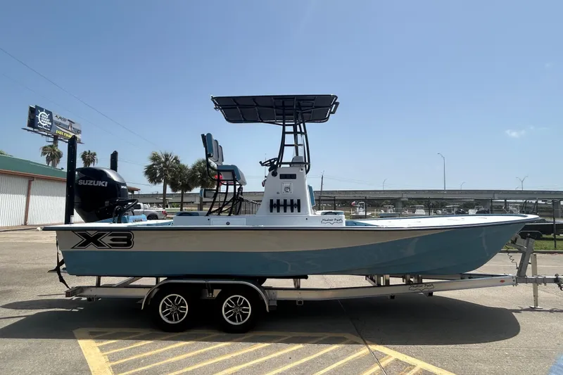 Slide: The Image of 2026 Shallow Sport 25 X3 boat on trailer, featuring Suzuki engine, parked outdoors. - 2