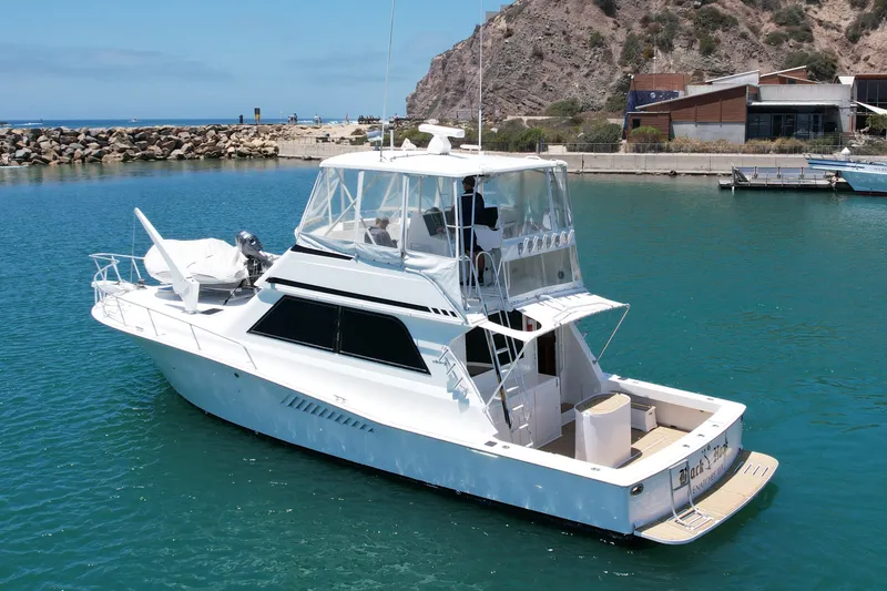 Slide: The Image of 1994 Viking 47 Convertible yacht docked in a serene marina setting. - 2