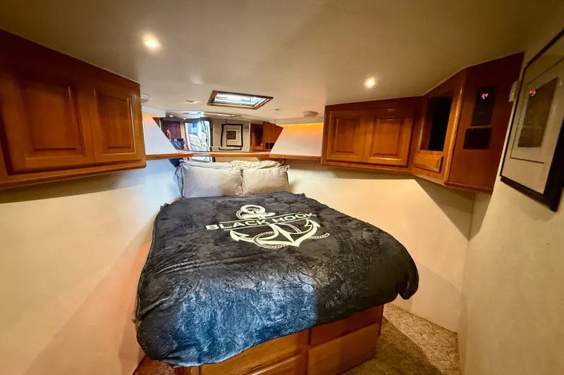 Slide: The Image of Cozy bedroom in 1994 Viking 47 Convertible yacht with wooden cabinets and nautical-themed bedding. - 26