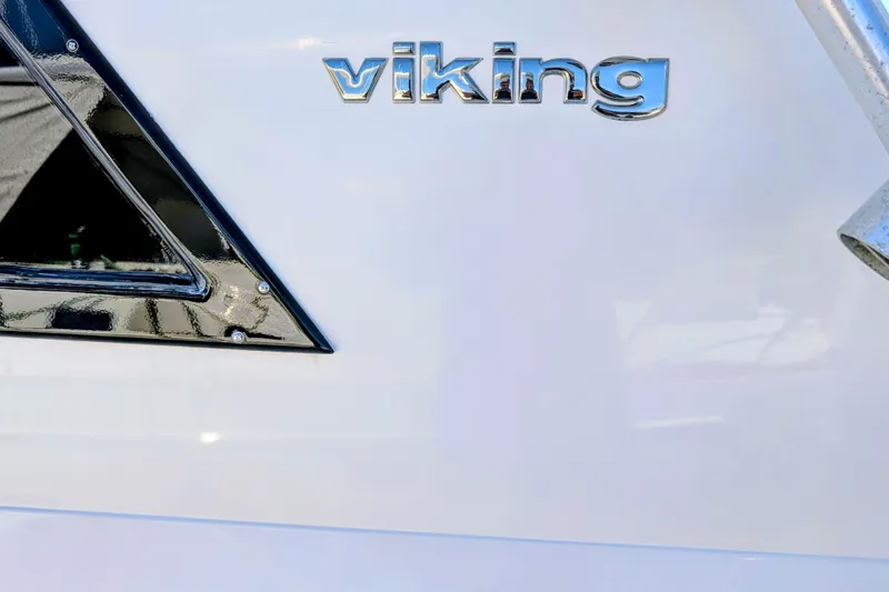 Slide: The Image of Viking 47 Convertible 1994 boat emblem on sleek white surface. - 81