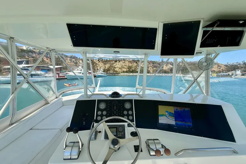 Slide: The Image of Helm of 1994 Viking 47 Convertible yacht with navigation screens, overlooking marina. - 60