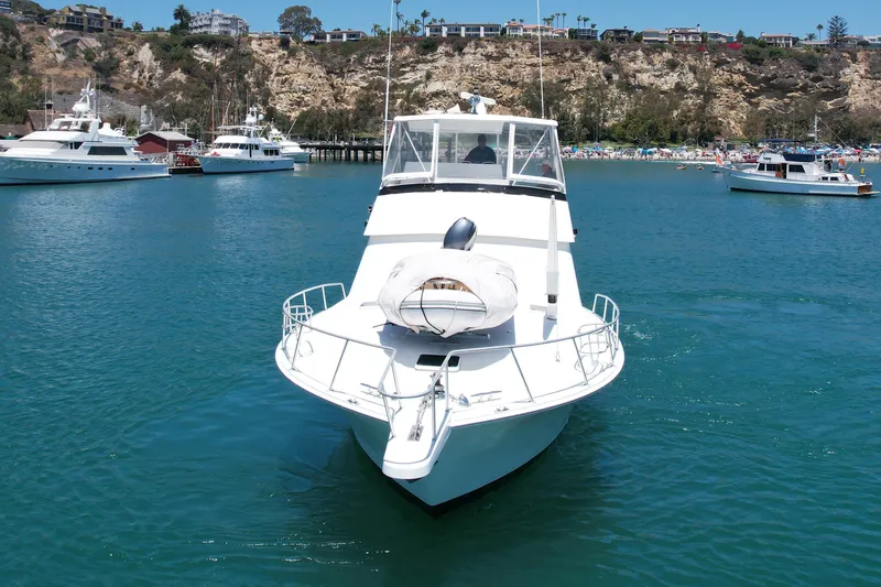 Slide: The Image of 1994 Viking 47 Convertible yacht cruising in a scenic harbor with cliffs and boats. - 3