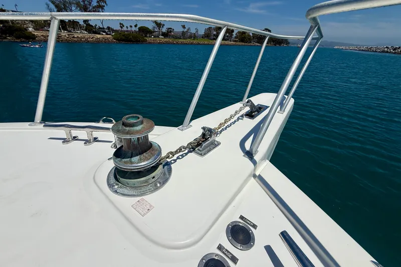 Slide: The Image of Bow of 1994 Viking 47 Convertible yacht with anchor chain and winch, on calm blue water. - 67