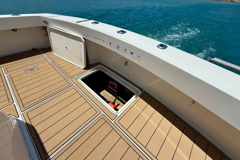 Slide: The Image of 1994 Viking 47 Convertible yacht deck with open storage hatch, overlooking blue ocean waters. - 46