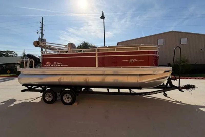 The Image of 2025 Sun Tracker Party Barge 20 DLX pontoon boat on trailer, outdoor setting. - 0
