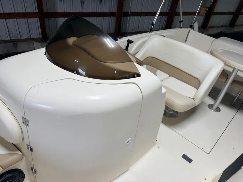 Slide: The Image of The image shows the cockpit of a Glastron DX215 deck boat with beige seating and a tinted windshield. - 23