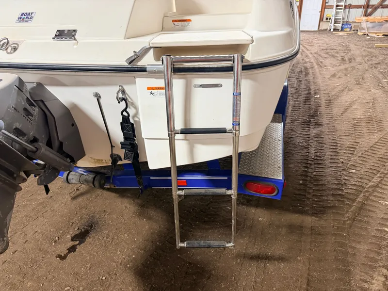 Slide: The Image of Rear of a Glastron boat with a retractable ladder and trailer on sandy ground. - 49