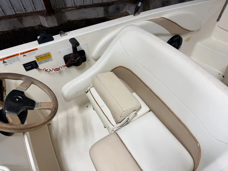 Slide: The Image of Interior view of a Glastron DX215 deck boat with beige seating and steering wheel. - 27