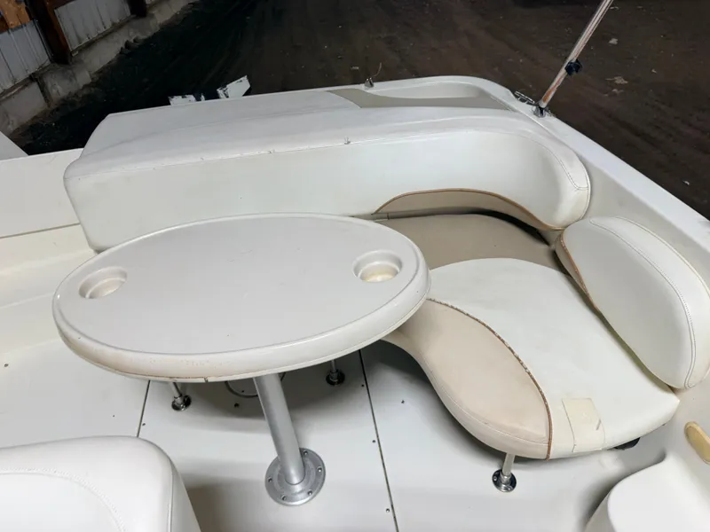 Slide: The Image of Interior of a Glastron DX215 deck boat with white seating and an oval table with cup holders. - 40