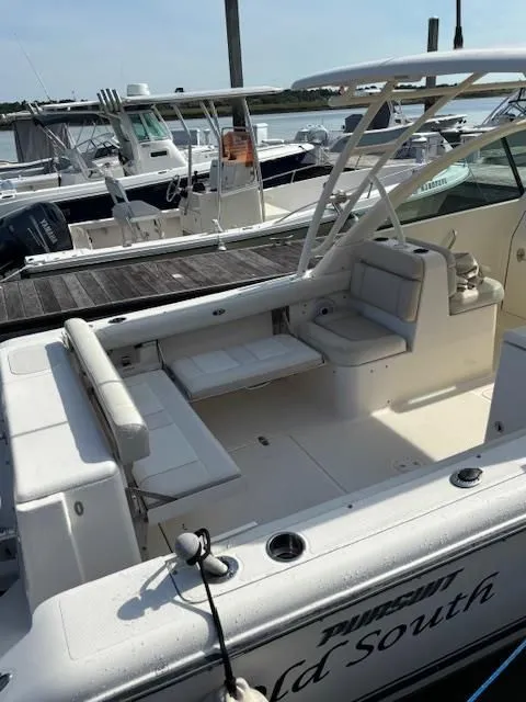 Slide: The Image of A 2012 Pursuit DC 265 Dual Console boat docked. It features white upholstery and an open deck. - 8