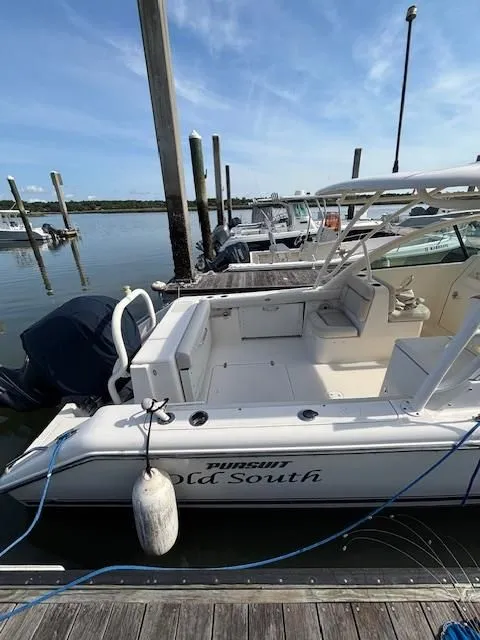 Slide: The Image of A 2012 Pursuit DC 265 Dual Console boat docked. It features an outboard motor. - 7