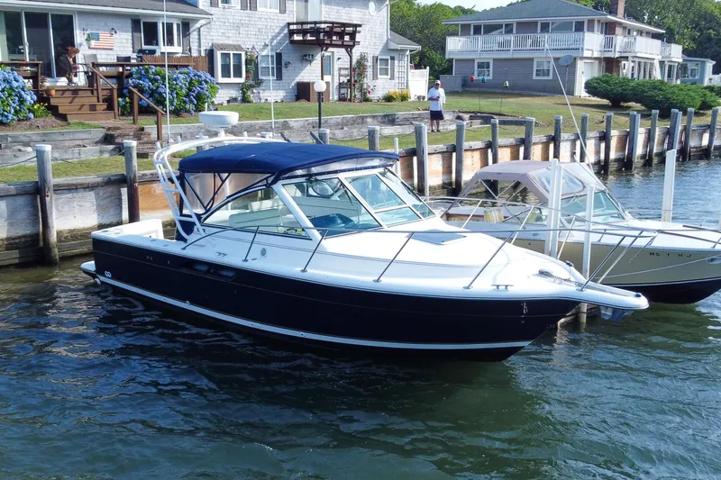The Image of 2001 Tiara Yachts 2900 Coronet docked by waterfront homes, showcasing sleek design. - 0
