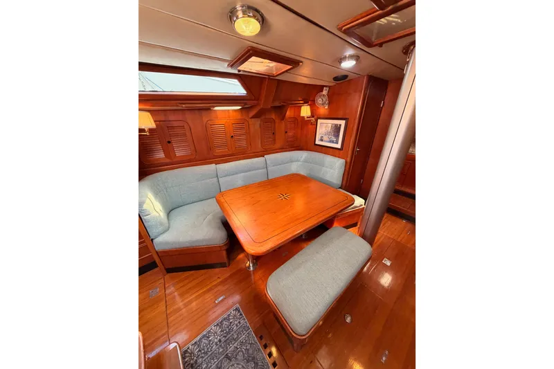 Slide: The Image of Cozy interior of 1991 Hylas 51 yacht with wooden dining area and cushioned seating. - 95