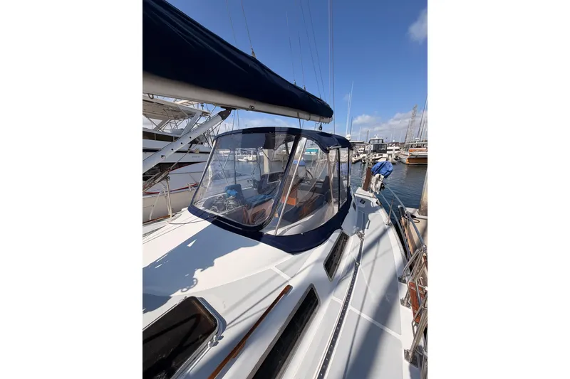Slide: The Image of 1991 Hylas 51 sailboat docked at marina, featuring sleek design and clear cockpit enclosure. - 25