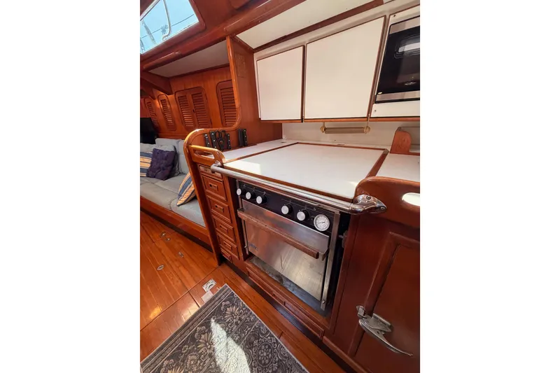Slide: The Image of Interior of 1991 Hylas 51 yacht featuring a wooden galley with stove and seating area. - 83