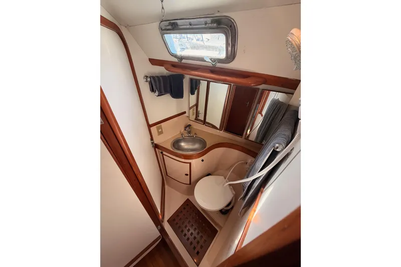 Slide: The Image of Compact bathroom in a 1991 Hylas 51 yacht with sink, toilet, and porthole window. - 100