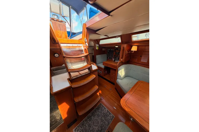 Slide: The Image of Interior of a 1991 Hylas 51 yacht featuring wooden stairs and cozy seating area. - 54