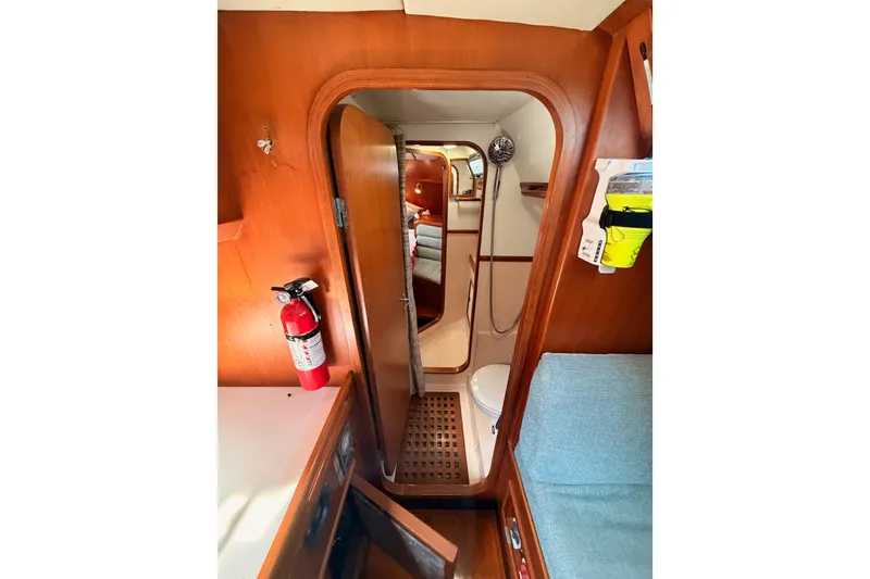 Slide: The Image of Interior of 1991 Hylas 51 yacht, featuring wooden cabinetry, a fire extinguisher, and a compact bathroom. - 67