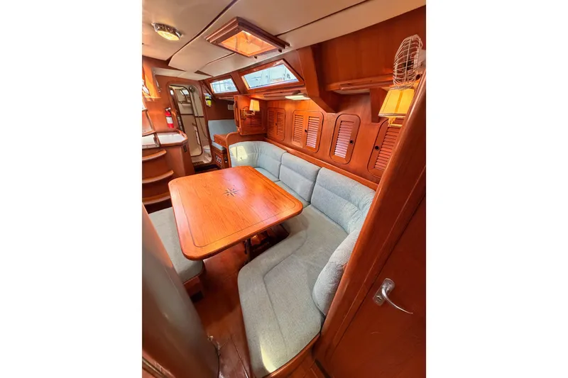 Slide: The Image of Cozy interior of 1991 Hylas 51 yacht with wooden dining area and cushioned seating. - 108