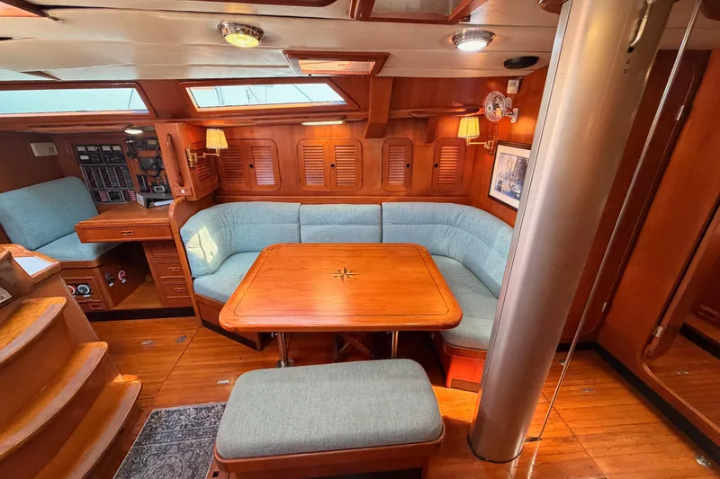Slide: The Image of Luxurious 1991 Hylas 51 yacht interior with wooden dining area and blue seating. - 53