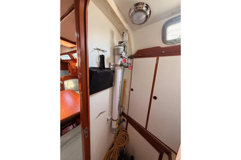 Slide: The Image of Interior of a 1991 Hylas 51 yacht, featuring a compact storage area and wooden cabinetry. - 99