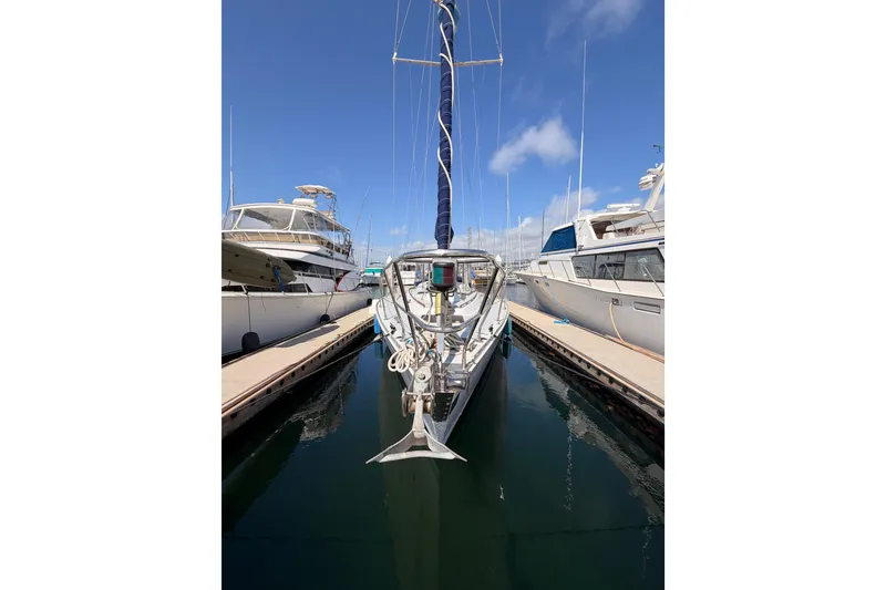 Slide: The Image of 1991 Hylas 51 sailboat docked between yachts under a clear blue sky. - 1