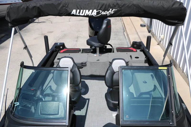 Slide: The Image of 2023 Alumacraft Competitor FSX 185 boat interior with seating and windshield, featuring a bimini top. - 21