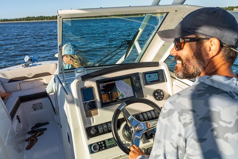 Slide: The Image of Manufacturer Provided Image: Man steering 2026 Sailfish 245 DC boat on open water, with advanced navigation system. - 6