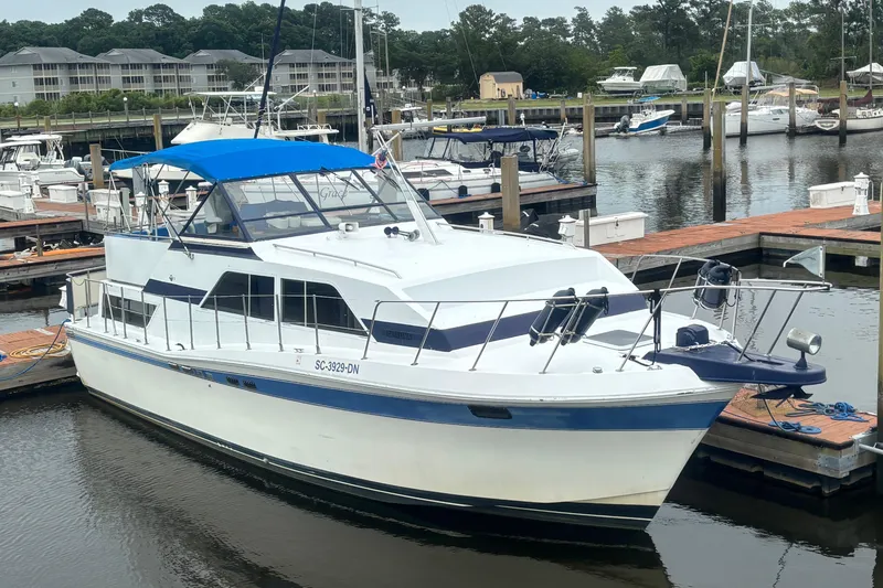The Image of 1984 Chris-Craft 381 Catalina yacht docked at a marina with blue canopy. - 0