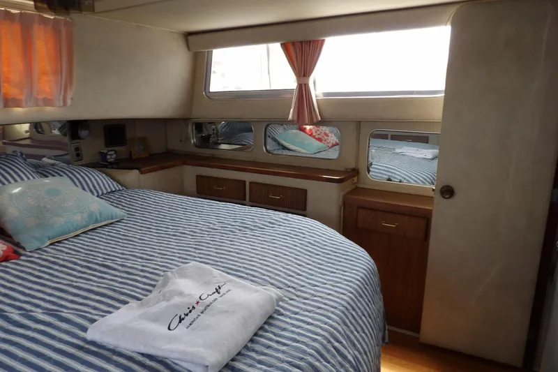 Slide: The Image of 1984 Chris-Craft 381 Catalina cabin interior with striped bedding and wooden cabinetry. - 29