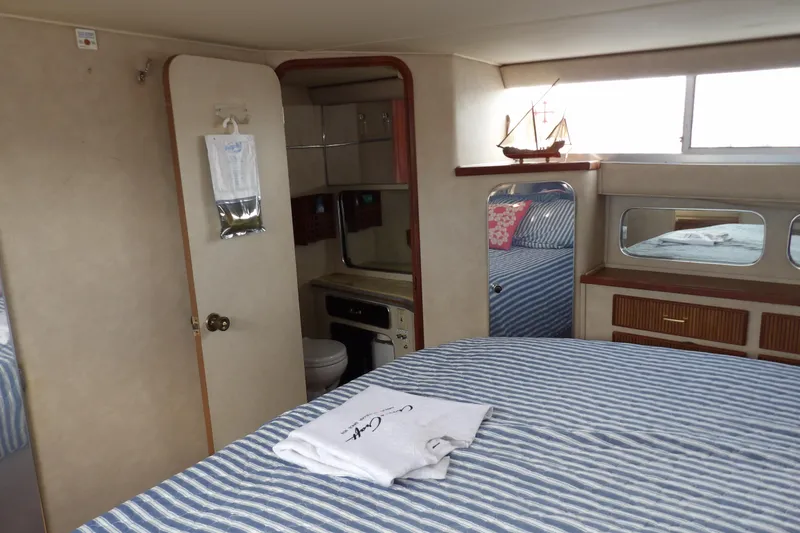 Slide: The Image of 1984 Chris-Craft 381 Catalina cabin interior with striped bedding and nautical decor. - 31