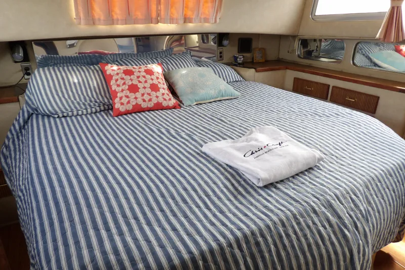 Slide: The Image of 1984 Chris-Craft 381 Catalina cabin with striped bedding and decorative pillows. - 28