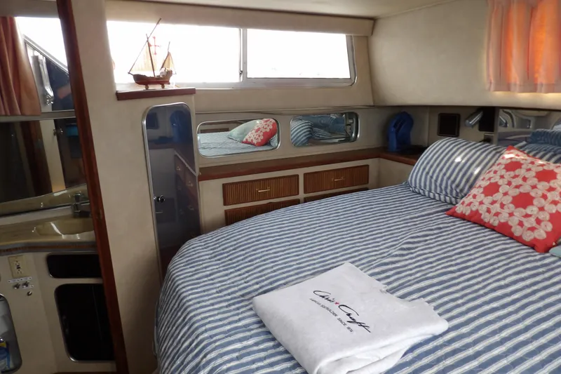 Slide: The Image of 1984 Chris-Craft 381 Catalina cabin interior with striped bedding and decorative pillows. - 30