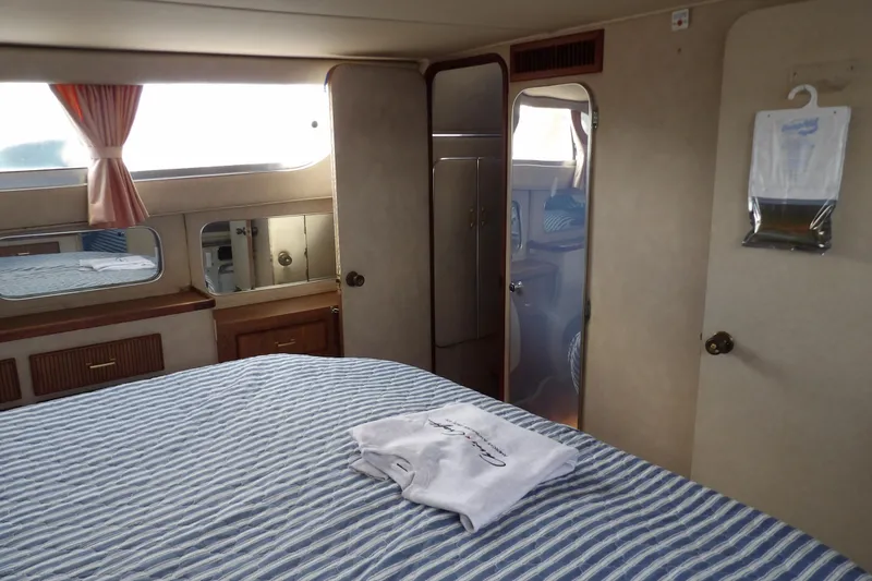 Slide: The Image of Interior of 1984 Chris-Craft 381 Catalina yacht with striped bedding and wooden cabinetry. - 32
