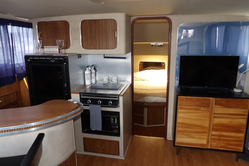 Slide: The Image of 1984 Chris-Craft 381 Catalina interior with kitchen, bed, and TV setup. - 20