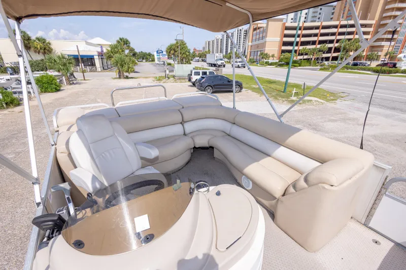 Slide: The Image of 2007 Crest 111 XRS pontoon boat with beige seating and canopy, parked near a road. - 20