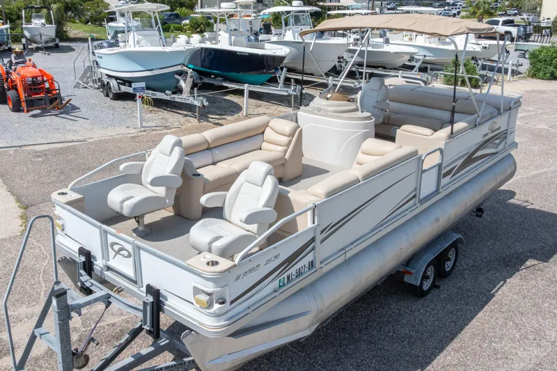Slide: The Image of 2007 Crest 111 XRS pontoon boat with beige seating, parked on a trailer in a marina. - 4