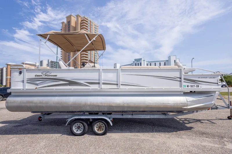 Slide: The Image of 2007 Crest 111 XRS pontoon boat on trailer, parked with buildings in background. - 5