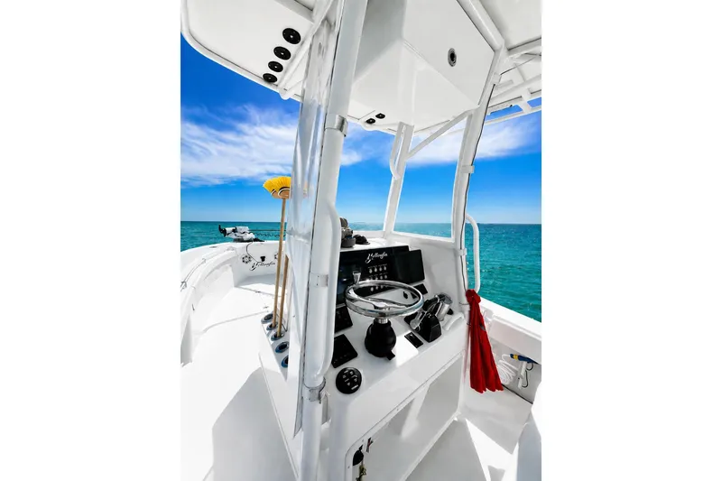 Slide: The Image of 2015 Yellowfin 26 Hybrid boat interior with steering console, ocean view, and clear blue sky. - 10