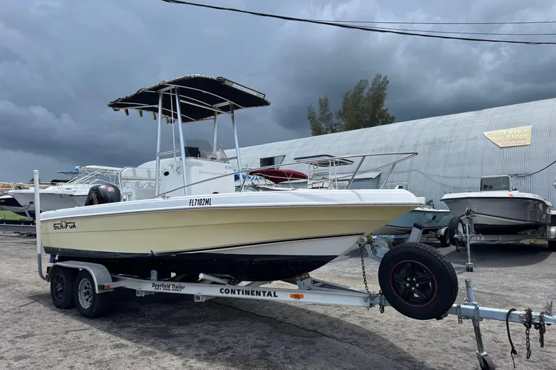 Slide: The Image of 2004 Sea Fox 225 Bay Fisher boat on trailer, parked outdoors under cloudy sky. - 1