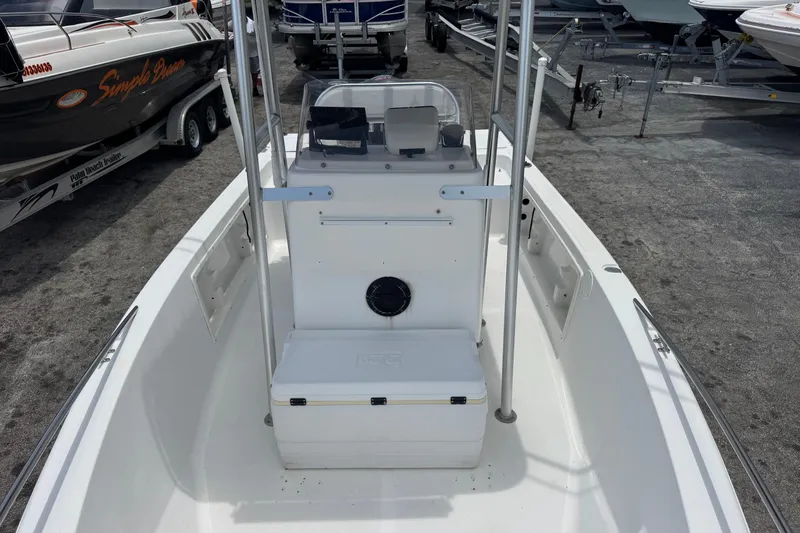 Slide: The Image of 2004 Sea Fox 225 Bay Fisher boat interior, featuring console and seating, in a marina setting. - 13