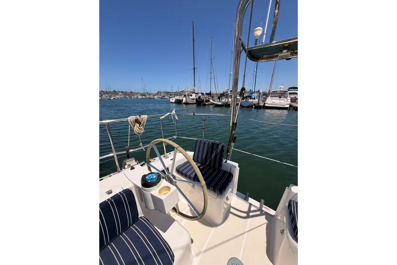 Slide: The Image of Sailboat deck view with striped seating, steering wheel, and marina backdrop; Saga 409, 2007 model. - 34