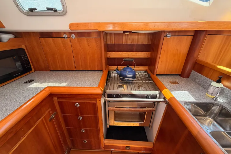 Slide: The Image of Wooden yacht kitchen with stove, microwave, and sink in a 2007 Saga 409 model. - 68