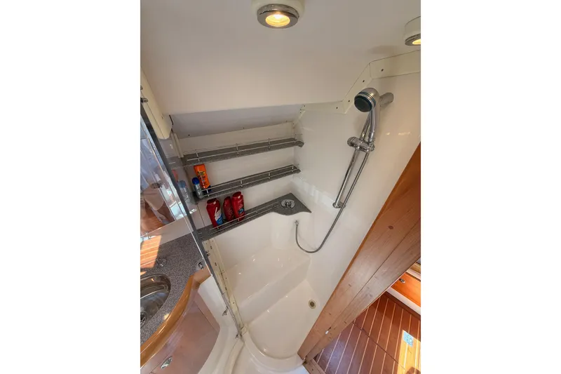 Slide: The Image of Compact bathroom with shower in 2007 Saga 409 boat, featuring shelves and wooden accents. - 99
