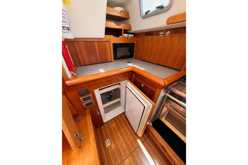 Slide: The Image of 2007 Saga 409 yacht interior kitchen with wooden cabinetry, microwave, and open fridge. - 62
